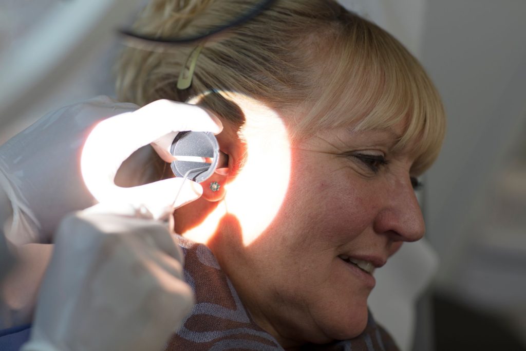 Women having her right ear canal cleaned using micro suction
