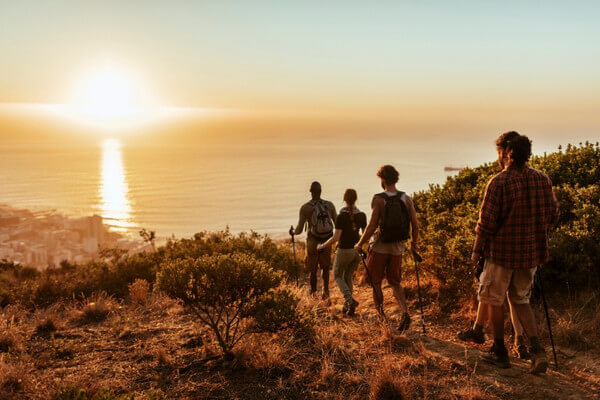 Group walking on a coastal trail at sunset