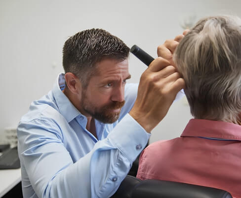 Audiologist examining an older patient’s ear with an otoscope