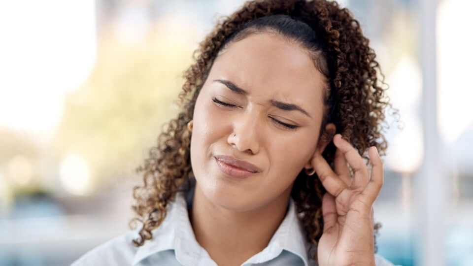 Woman touching her ear while experiencing hearing discomfort